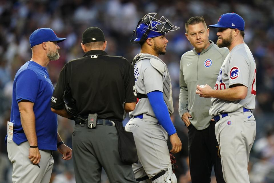 A trainer checks on Chicago Cubs' pitcher Wade Miley, right, as Miley talks to catcher Willson Contreras, center, before leaving a baseball game during the fourth inning against the New York Yankees, Friday, June 10, 2022, in New York. (AP Photo/Frank Franklin II)