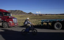Un ciclista pasa junto a camiones de carga atascados en Desaguadero, Bolivia, en la frontera con Perú, sin poder cruzar debido a los bloqueos de carreteras por las protestas antigubernamentales en Perú, el viernes 13 de enero de 2023. (AP Foto/Juan Karita)