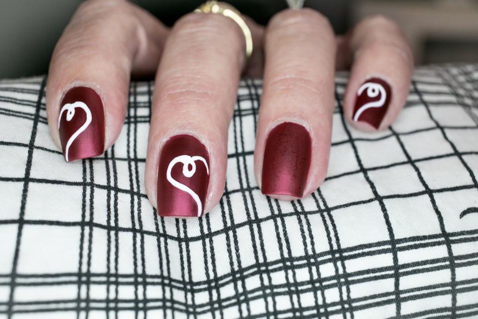 <p>This sophisticated burgundy polish is offset by swirly open hearts. Paint them on every nail, or just choose a few to make a statement.</p>