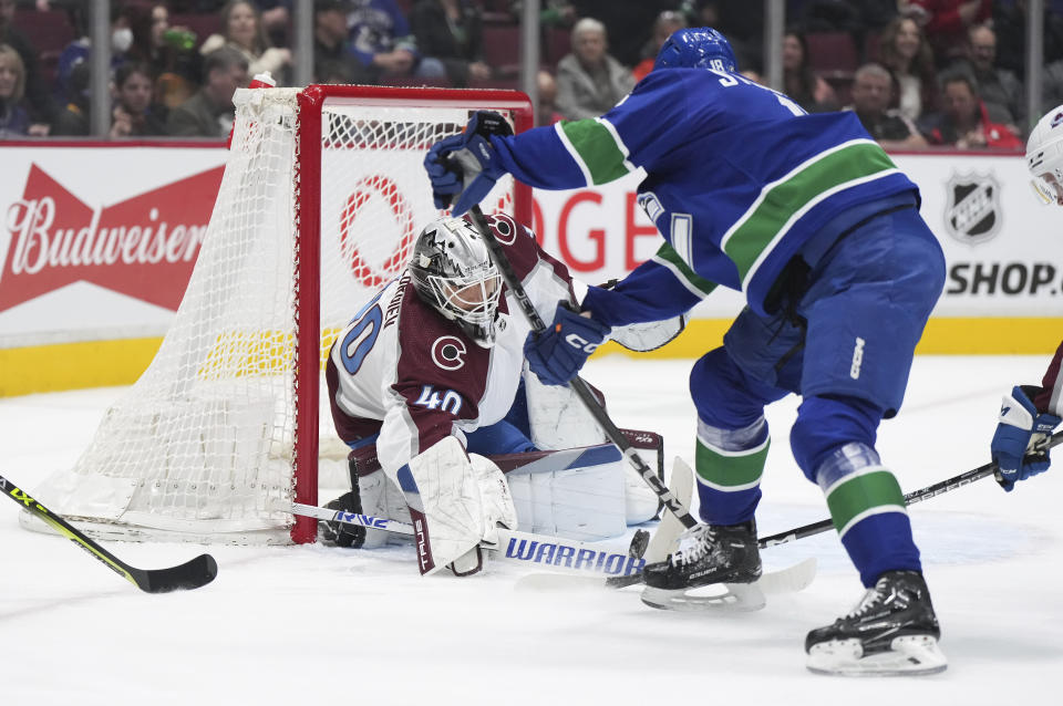 Colorado Avalanche goalie Alexandar Georgiev, back left, of Russia, stops Vancouver Canucks' Jack Studnicka during the first period of an NHL hockey game in Vancouver, British Columbia on Thursday, Jan. 5, 2023. (Darryl Dyck/The Canadian Press via AP)