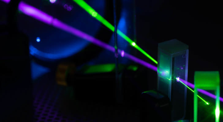 A photo of a purple and green laser going through an object