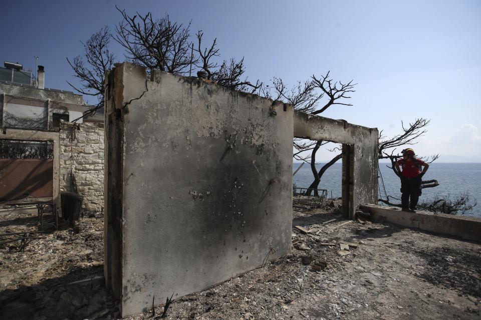 A member of a rescue team searches a burned house in Mati, east of Athens, Wednesday, July 25, 2018. Rescue crews were searching Wednesday through charred homes and cars for those still missing after the deadliest wildfires to hit Greece in decades decimated seaside areas near Athens, killing at least 79 people and sending thousands fleeing. (AP Photo/Thanassis Stavrakis)