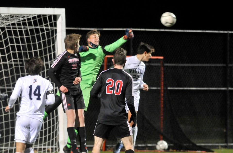 Victor goalkeeper Connor Cronin punches the ball out of danger after a Penfield corner kick during a Class AA match.