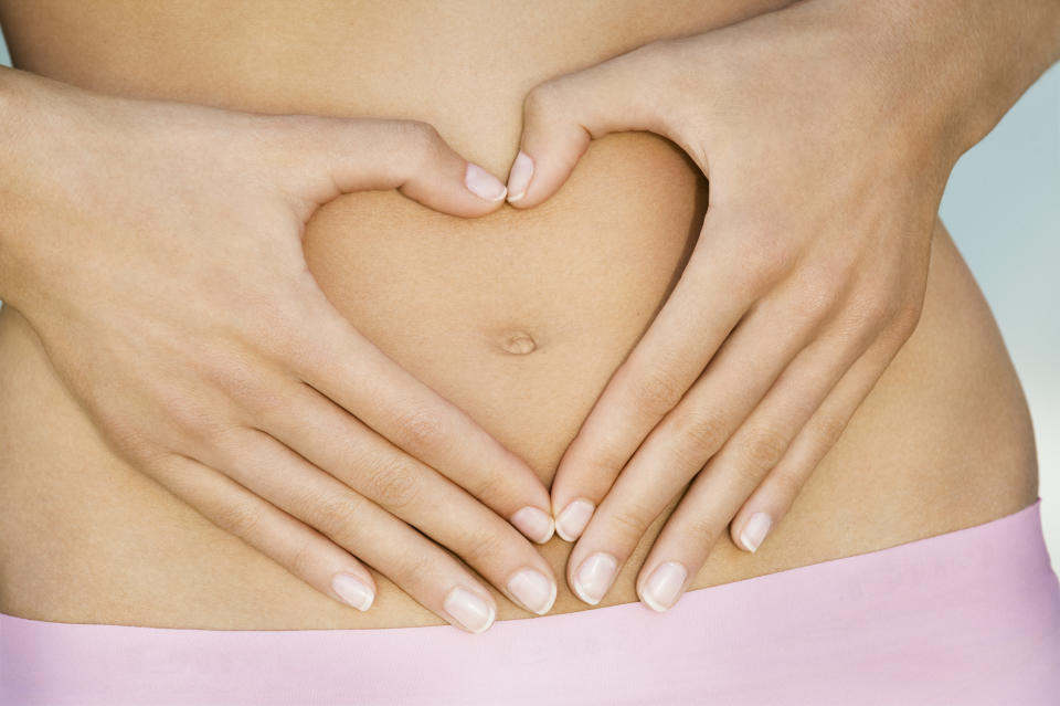 Close-up on 22 years old woman hands framing a heart on her slim stomach around her navel , she is wearing pink panties, high section, France, Nice