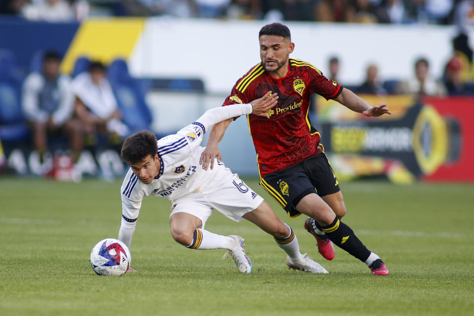 LA Galaxy midfielder Riqui Puig, left, and Seattle Sounders midfielder Cristian Roldan eye the ball during the second half of an MLS soccer match in Carson, Calif., Saturday, April1, 2023. (AP Photo/Ringo H.W. Chiu)