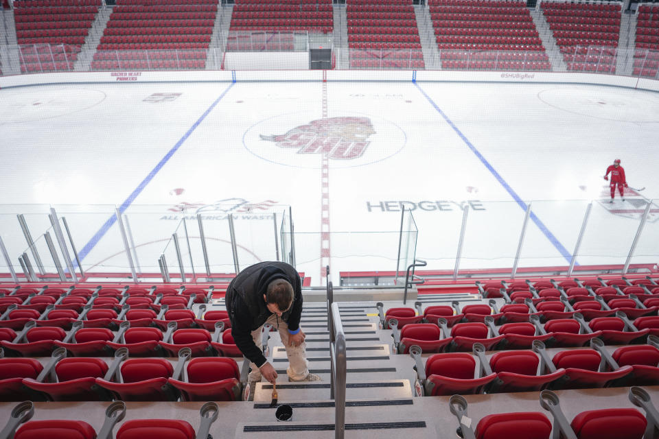 A worker paints the steps at the newly constructed NCAA college hockey Martire Family Arena on the campus of Sacred Heart University in Fairfield, Conn., Monday, Jan 9, 2023. (AP Photo/Bryan Woolston)