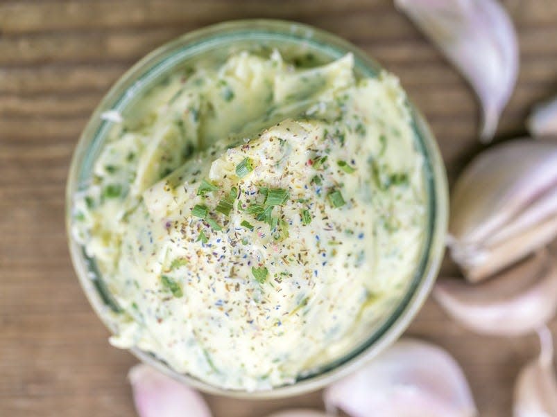 garlic butter in a jar surrounded by cloves of garlic