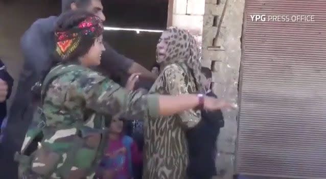 A woman liberated from ISIS tears off her burqa. Photo: YPG