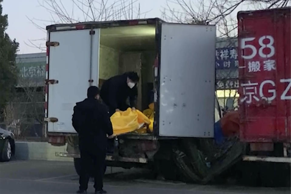 Workers load body bags into a truck at a funeral complex in Beijing, Friday, Dec. 16, 2022. Deaths linked to COVID are beginning to appear in China, even as those deaths are not reflected in the official tally. Relatives of people who died in Beijing said their loved ones had tested positive for the coronavirus before their deaths, while employees at shops in one funeral complex said there has been a noticeable uptick in traffic in the past few days. (AP Photo/Dake Kang)