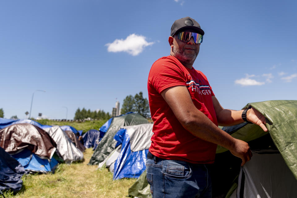 Jose Guerrero, of Puerto Cabello, Venezuela, stands near his tent at an encampment of asylum-seekers mostly from Venezuela, Congo and Angola next to an unused motel owned by the county, Wednesday, June 5, 2024, in Kent, Washington. (AP Photo/Lindsey Wasson)
