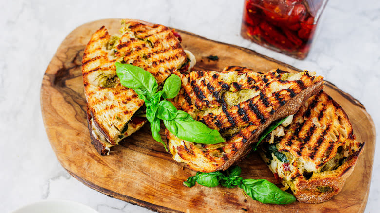 three chicken panini sandwiches on a cutting board