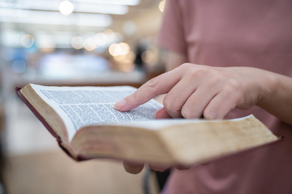 Person reading and pointing at a page in an open book, indicating focus on specific text