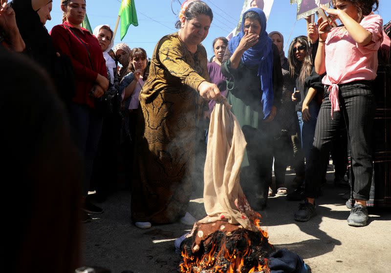 Women burn headscarves during a protest over the death of Mahsa Amini in Iran, in the Kurdish-controlled city of Qamishli