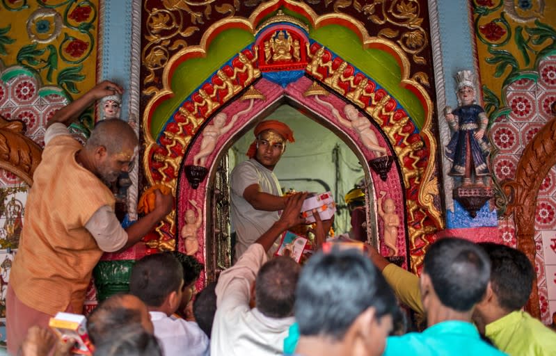 A Hindu priest distributes sweets as 'Prasad' (holy offerings) after a prayer session inside a temple in Ayodhya