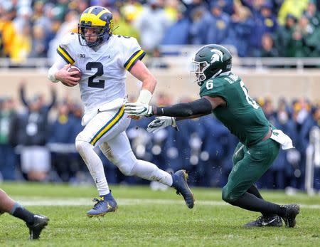 Oct 20, 2018; East Lansing, MI, USA; Michigan Wolverines quarterback Shea Patterson (2) runs though the tackle of Michigan State Spartans safety David Dowell (6) during the second half of a game at Spartan Stadium. Mandatory Credit: Mike Carter-USA TODAY Sports