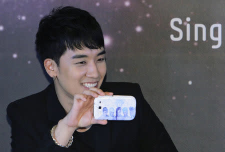 Seungri (Lee Seung-hyun) of South Korean band "Big Bang" poses with a Samsung Galaxy S3 phone sporting a cover with an image of the band on it during a pre-concert news conference in Singapore September 27, 2012. REUTERS/Tim Chong/Files