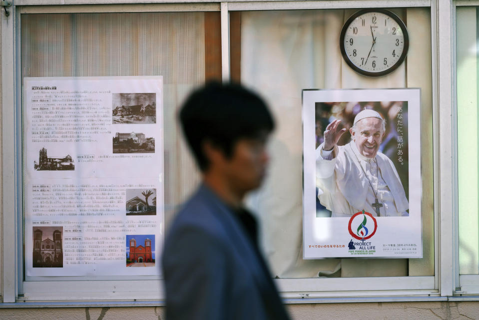In this Nov. 16, 2019, photo, a man walks by a poster of Pope Francis at the Urakami Cathedral in Nagasaki, southern Japan. Pope Francis will start his first official visit to Japan in Nagasaki, ground zero for the Christian experience in a nation where the Catholic leader once dreamed of living as a missionary. (AP Photo/Eugene Hoshiko)