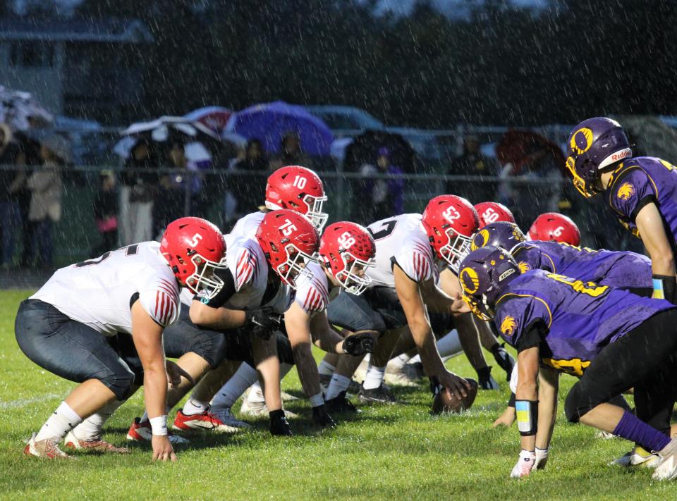 The Clinton offense and Onsted defense line up for a play in the rain Friday at Onsted.