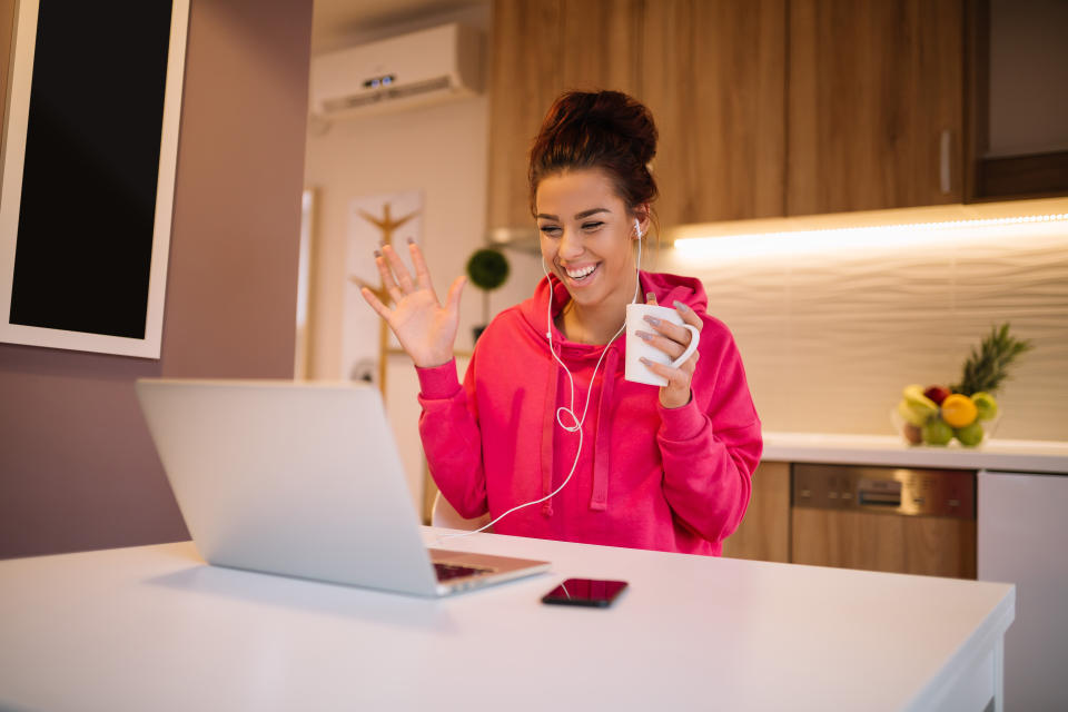 Young beautiful girl video chatting. Girl with smile on her face waving to the camera on her laptop.