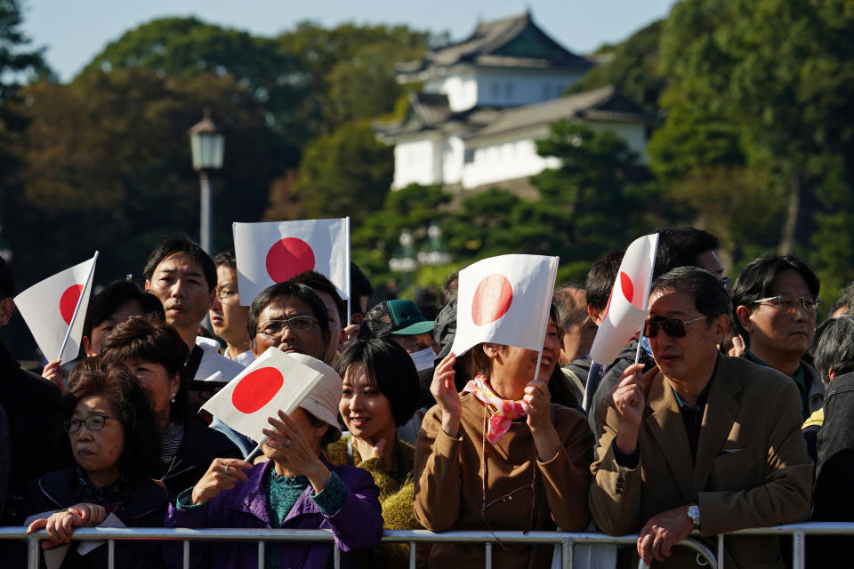 Japanese well-wishers hold Japanese national flag at the Imperial Palace before the royal parade of Japanese Emperor Naruhito and Empress Masako in Tokyo, Sunday, Nov. 10, 2019. (AP Photo/Eugene Hoshiko)