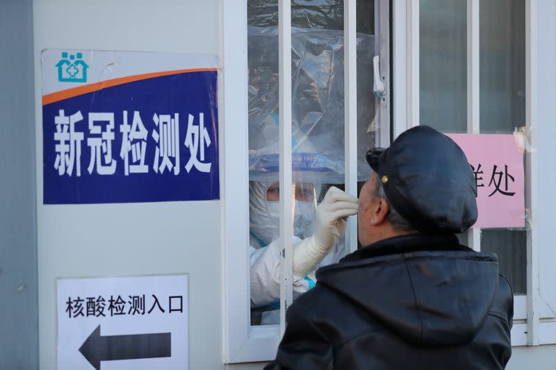 Medical worker collects a swab from a man for nucleic acid testing at a hospital in Shenyang