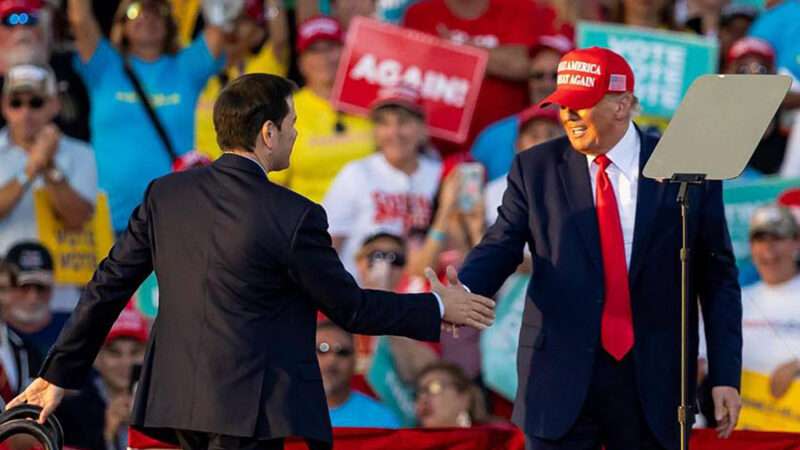 Marco Rubio shakes hands with Donald Trump on a stage at a rally