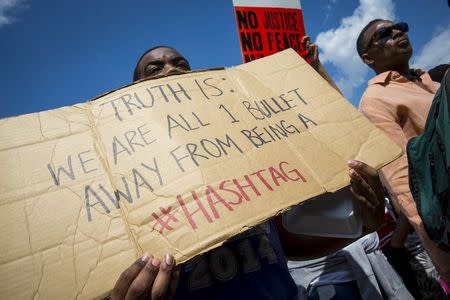 Demonstrators hold signs at a rally at City Hall in Baltimore, Maryland May 2, 2015. REUTERS/Eric Thayer