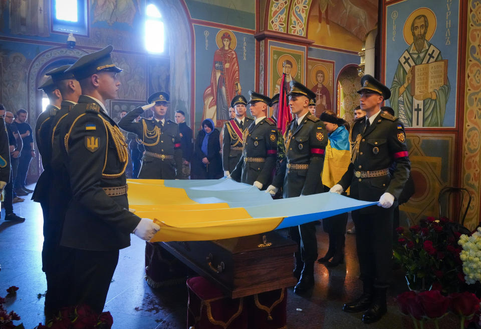 Soldiers place the Ukrainian flag on the coffin of volunteer soldier Oleksandr Makhov, 36 a well-known Ukrainian journalist, killed by the Russian troops, at St Michael cathedral in Kyiv, Ukraine, Monday, May 9, 2022. (AP Photo/Efrem Lukatsky)