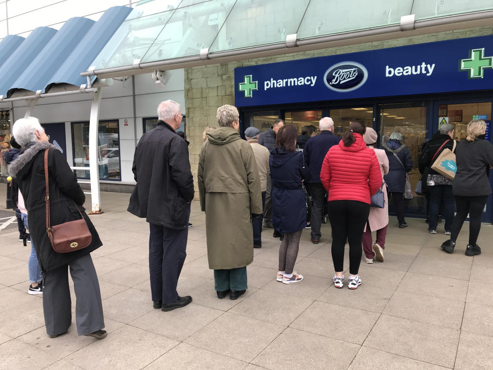 People queue outside a Boots pharmacy store in west London where stocks of hand sanitiser are limited to two per person. (Photo by Martin Keene/PA Images via Getty Images)