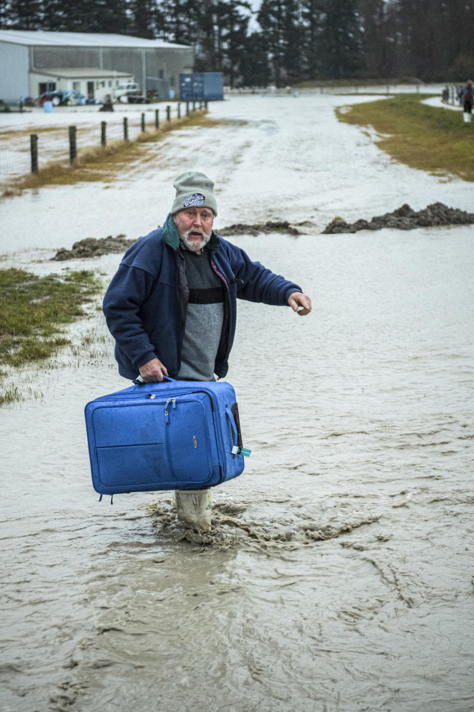 A man carries his suitcase as he is evacuated from floods by New Zealand Defense Force personnel near Ashburton in New Zealand's South Island, Sunday May 30, 2021. Several hundred people in New Zealand were evacuated from their homes Monday, May 31, 2021 as heavy rainfall caused flooding in the Canterbury region. (Corp. Sean Spivey/NZDF via AP)