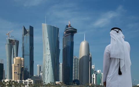 A man looks at the Doha skyline in Qatar - Credit: Cultura RM Exclusive/Lost Horizon Images