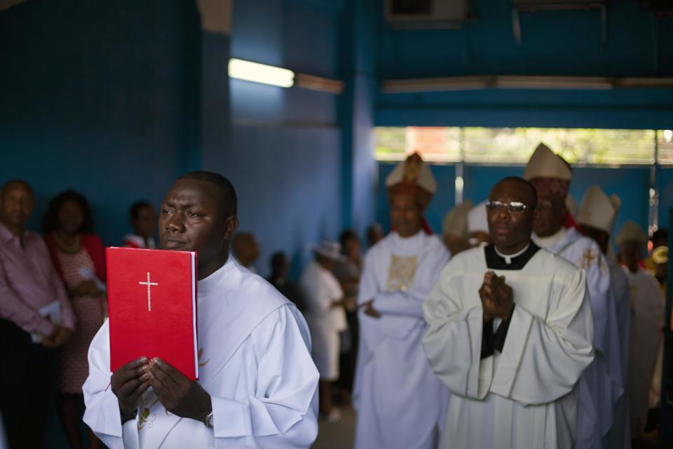 A priest carries a book during a Mass lead by Cardinal Chibly Langlois in Port-au-Prince, Haiti, Sunday, March 9, 2014. Haiti's first cardinal held his first Mass since he was appointed by Pope Francis in January. (AP Photo/Dieu Nalio Chery)