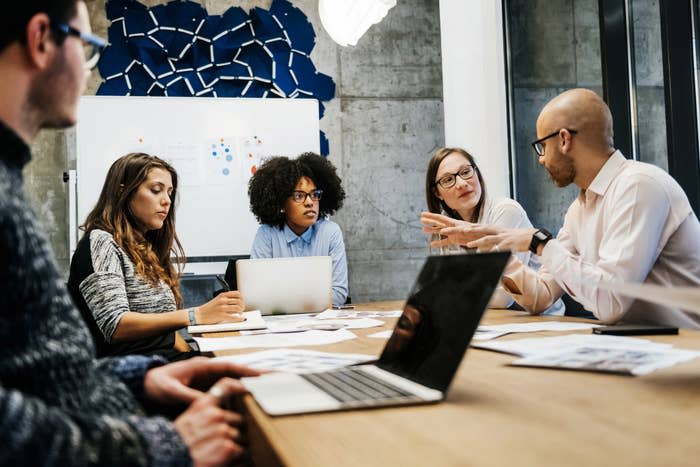 A group of men and women with laptops having a meeting