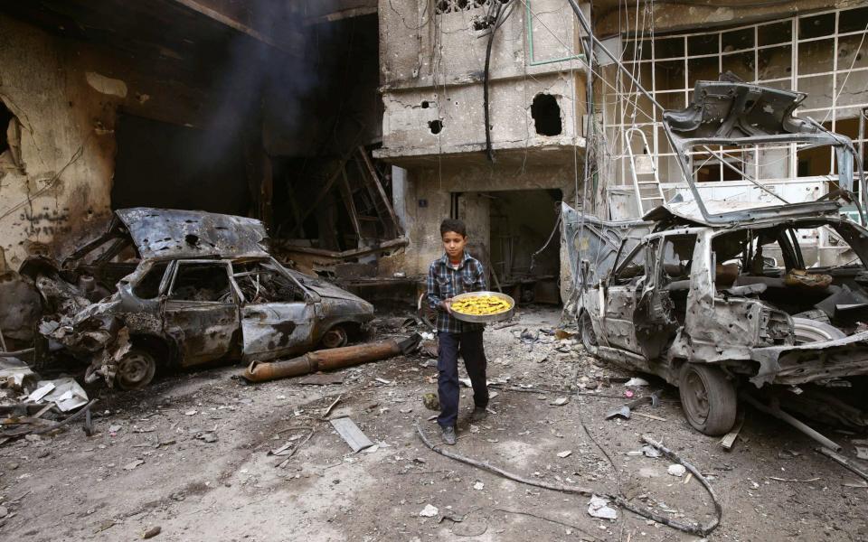 A boy holds a tray of cookies in the besieged town of Douma, Eastern Ghouta - REUTERS