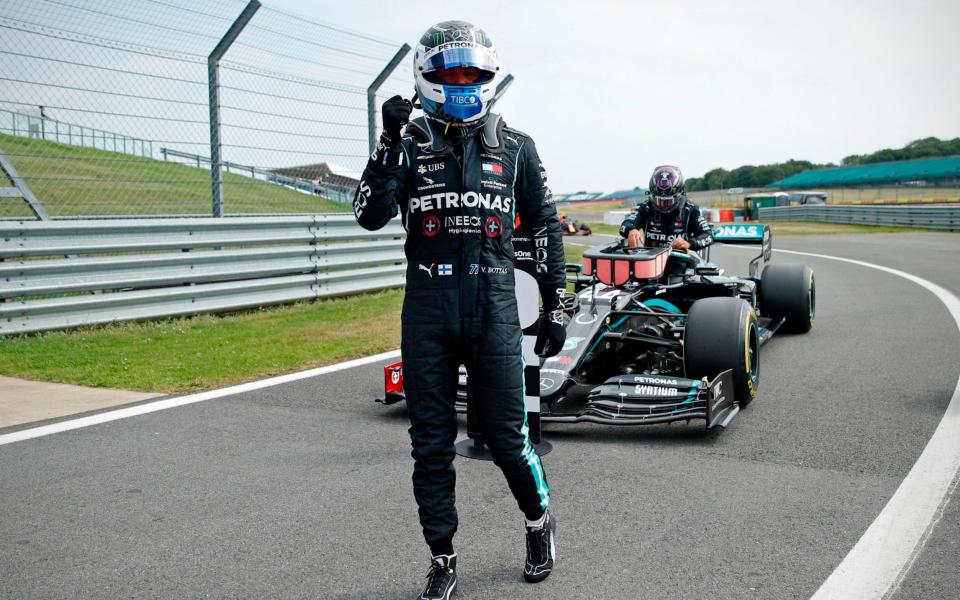 Mercedes' Finnish driver Valtteri Bottas celebrates in the pit lane after taking pole position as Mercedes' British driver Lewis Hamilton (back) gets out of his car during the qualifying session of the F1 70th Anniversary Grand Prix at Silverstone on August 8, 2020 in Northampton. - This weekend's race will commemorate the 70th anniversary of the inaugural world championship race, held at Silverstone in 1950. - ANDREW BOYERS/POOL/AFP via Getty Images