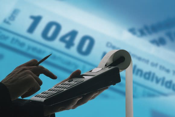 An accountant using a calculator with form 1040 in the background.