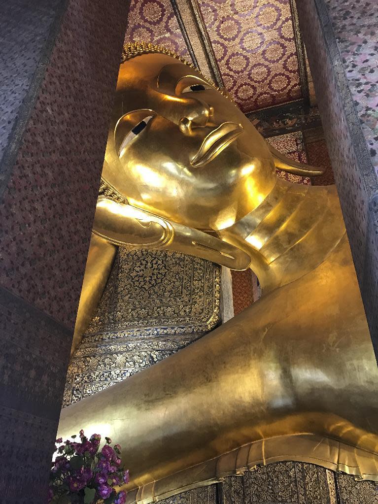 In this Dec. 9, 2016 photo, a massive Buddha statue is the main attraction at Wat Pho, or the Temple of the Reclining Buddha, in Bangkok. The golden statue fills the temple from end to end and lies in a complex that boasts a series of opulent buildings and a school where Thai massage originated. (AP Photo/Courtney Bonnell)