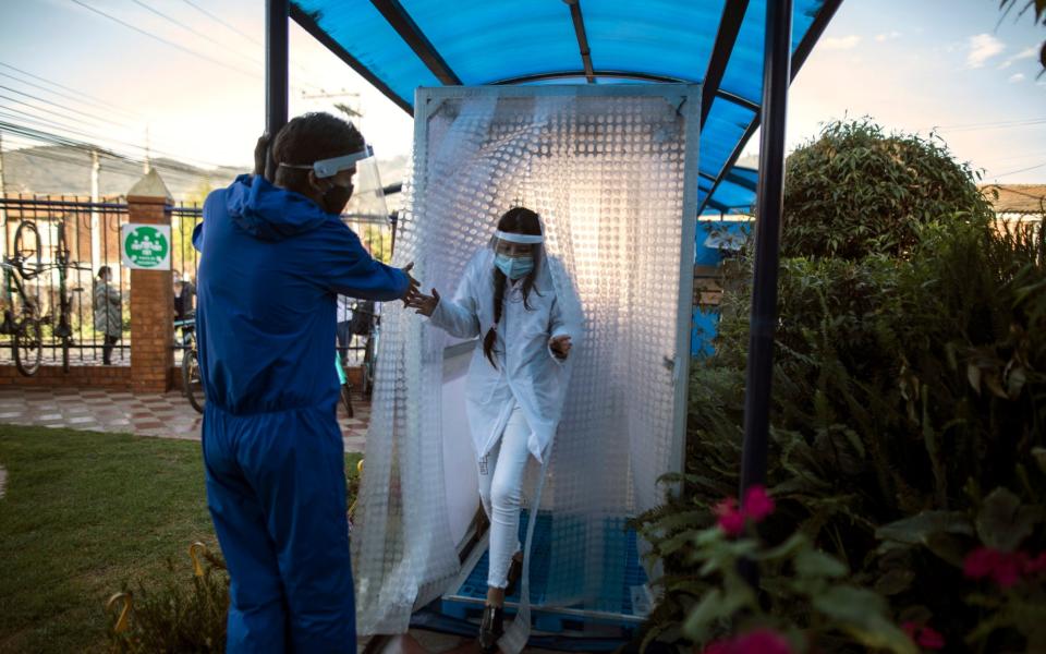 A student wearing protective gear exits a disinfection area on the first day back to in-person class since Spring last year at Liceo Lunita, a private school in Chia on the outskirts of Bogota - AP Photo/Ivan Valencia)