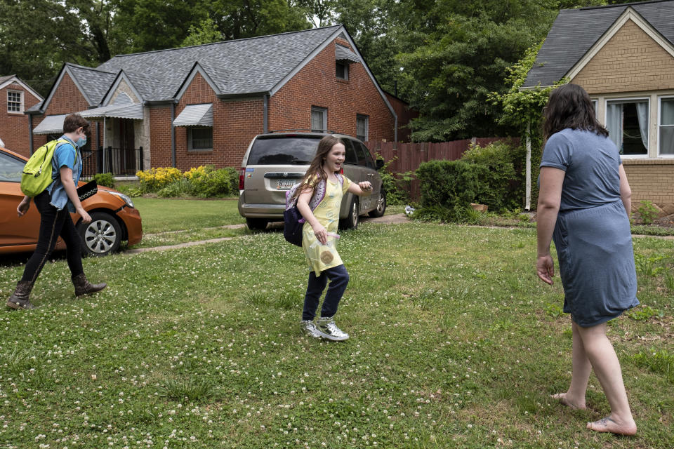 Abby Norman greets her daughters Juliet, 11, left, and Priscilla, 9, as they arrive home from school to the family's Decatur, Ga. home on Tuesday, May 18, 2021. Priscilla was in tears the first morning of testing this year because she felt pressure to do well, but didn't feel prepared after remote learning. (AP Photo/Ben Gray)
