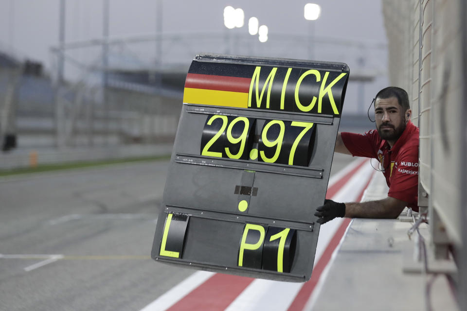 A Ferrari team member shows a pit board to Mick Schumacher during his first F1 test for Ferrari at the Bahrain International Circuit in Sakhir, Bahrain, Tuesday, April 2, 2019. Mick Schumacher has moved closer to emulating his father Michael by driving a Ferrari Formula One car in an official test. Schumacher's father won seven F1 titles, five of those with Ferrari and holds the record for race wins with 91. (AP Photo/Hassan Ammar)