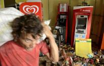 A man carries goods out of a supermarket that was looted during a police strike in Salvador, Bahia state, April 17, 2014. A police strike has unleashed violent crime in Brazil's third-largest city just two months before it is set to welcome hordes of soccer fans for the World Cup, adding to fears about the country's ability to ensure safety during the event. At least 22 people were killed in and around the northeastern city of Salvador after state police went on strike early on Wednesday to demand better pay and other benefits, the Bahia state government said on Thursday, prompting the federal government to dispatch troops to restore order. REUTERS/Valter Pontes (BRAZIL - Tags: CRIME LAW POLITICS CIVIL UNREST SPORT SOCCER WORLD CUP)