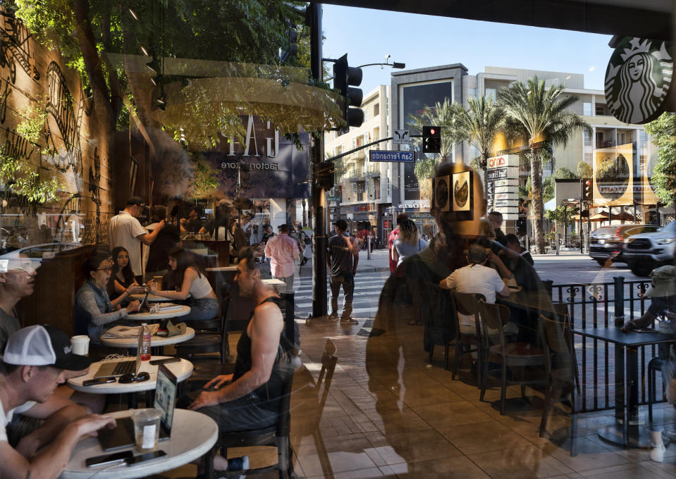 FILE - In this Aug. 8, 2019, file photo customers are seen through the window of a Starbucks coffee shop as a city street is reflected walk out of a Starbucks coffee shop in Burbank, Calif. On Thursday, Aug. 15, the Commerce Department releases U.S. retail sales data for July. (AP Photo/Richard Vogel, File)