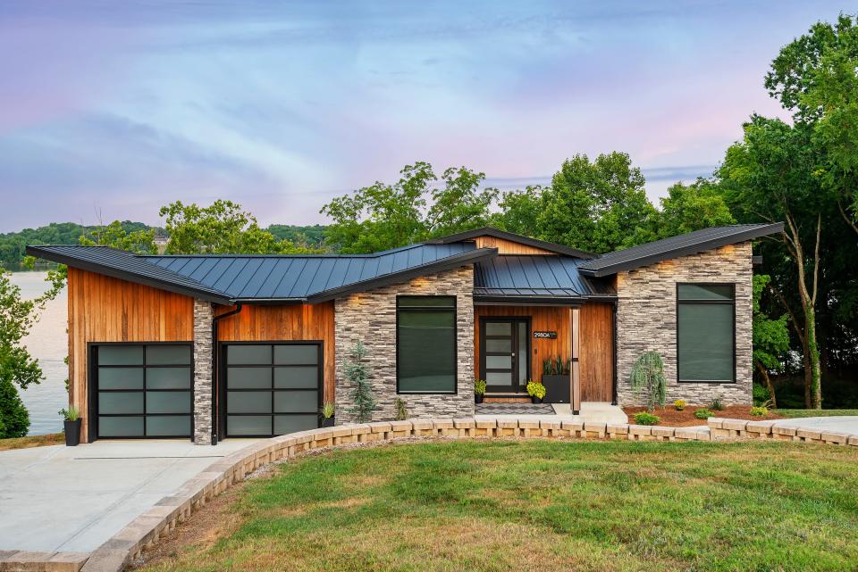 The home's exterior features modern lines, stonework, and wood siding.