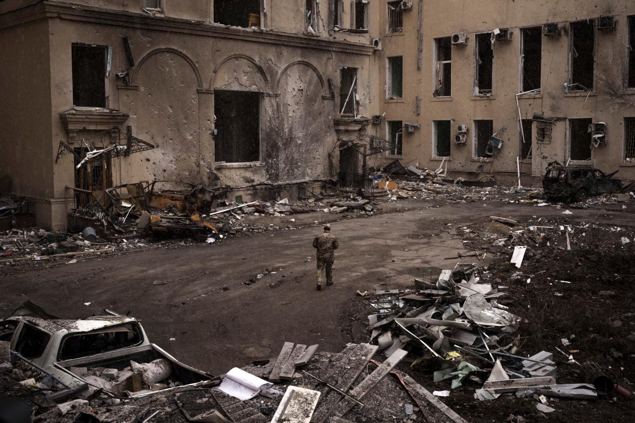 A Ukrainian serviceman walks outside the regional administration building, heavily damaged after a Russian attack earlier this month in Kharkiv, Ukraine, Sunday, March 27, 2022.