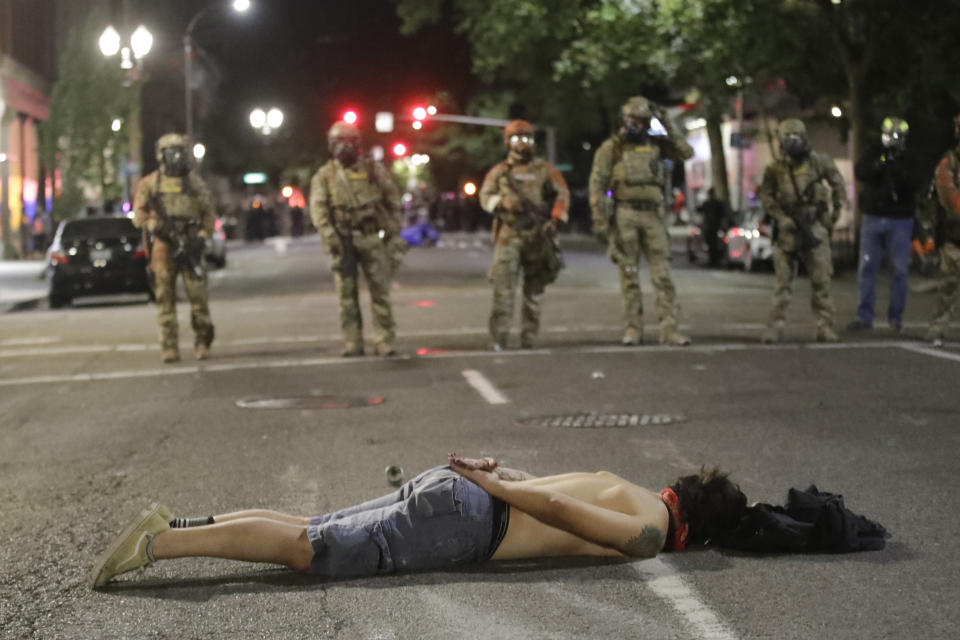 A demonstrator lays down in front of federal officers during a Black Lives Matter protest at the Mark O. Hatfield United States Courthouse Sunday, July 26, 2020, in Portland, Ore. (AP Photo/Marcio Jose Sanchez)