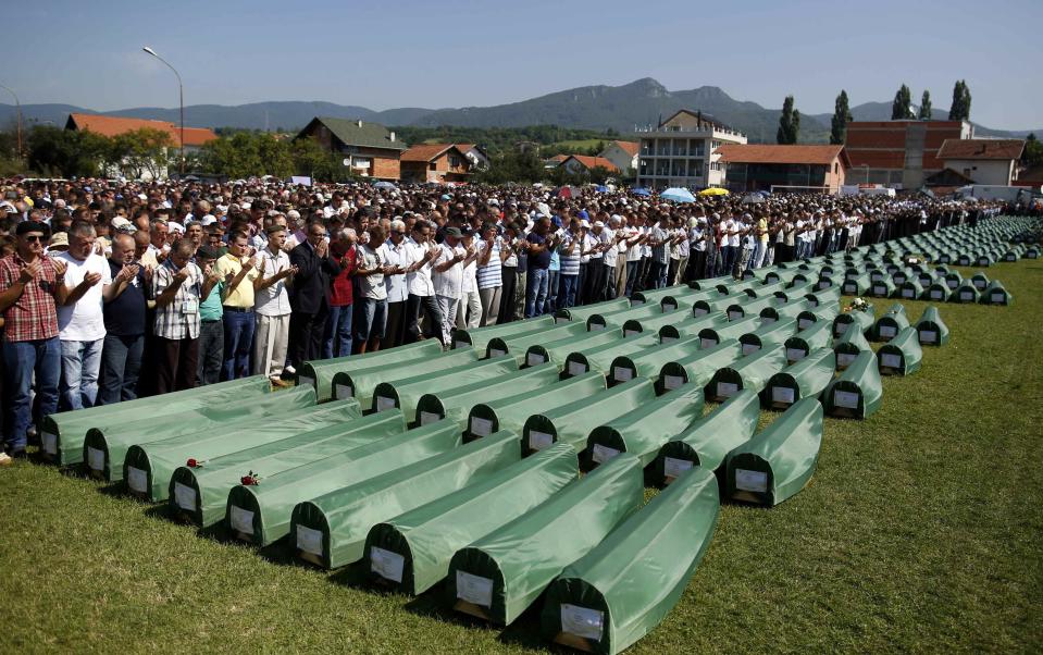 Bosnian Muslims pray near the coffins of relatives during mass funeral for bodies found in a mass grave, in Kozarac, near Prijedor, July 20, 2014. (REUTERS/Dado Ruvic)