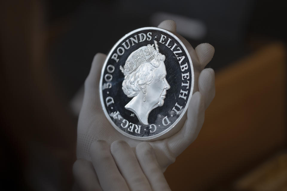 A coin featuring the portrait Queen Elizabeth II, is assessed during the "Trial of the Pyx,'' a ceremony that dates to the 12th Century in which coins are weighed in order to make certain they are up to standard, at the Goldsmiths' Hall in London, Tuesday, Feb. 7, 2023. A jury sat solemnly in a gilded hall in central London on Tuesday, presided over by a bewigged representative of the crown in flowing black robes, but there were no criminals in the dock. (AP Photo/Kin Cheung)