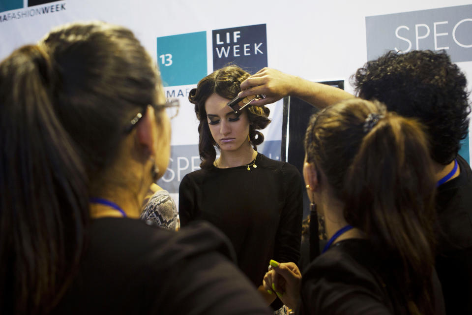 In this April 9, 2013 photo, stylists work together to prepare a model backstage prior to a show at Lima Fashion Week in Lima, Peru. (AP Photo/Martin Mejia)