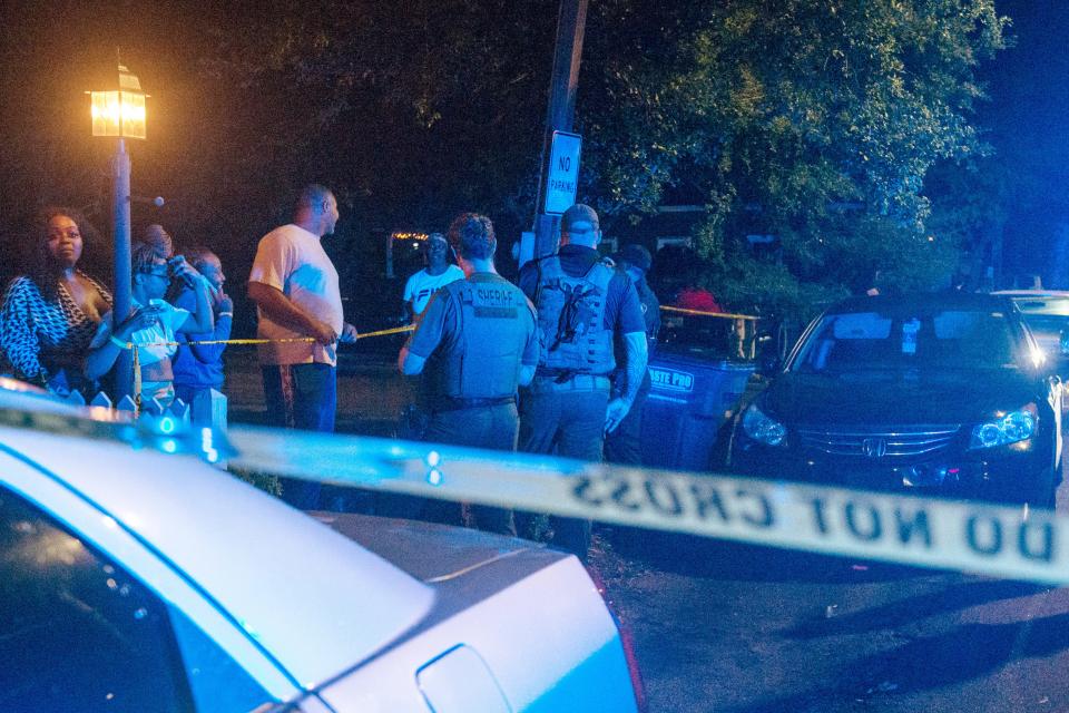 Law enforcement officers stand behind crime scene tape as onlookers watch an investigation into a shooting during a Cinco de Mayo party at The Scratch Kitchen restaurant late Friday, May 5, 2023, in Ocean Springs, Miss.