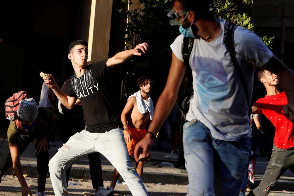 Demonstrators throw stones during a protest (REUTERS)